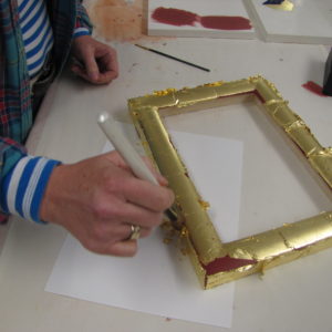 Brushing off skewings after the first laying of leaf before patching the missing areas of gilding with more gold